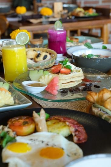 Breakfast spread with pancakes, fresh fruit, croissants, toast and juice
